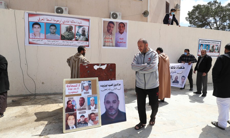 Family members of the victims show the photos of the victims during the funeral in the Libyan city of Tarhuna, some 90 km south of the capital Tripoli, on March 26, 2021.(Photo: Xinhua)