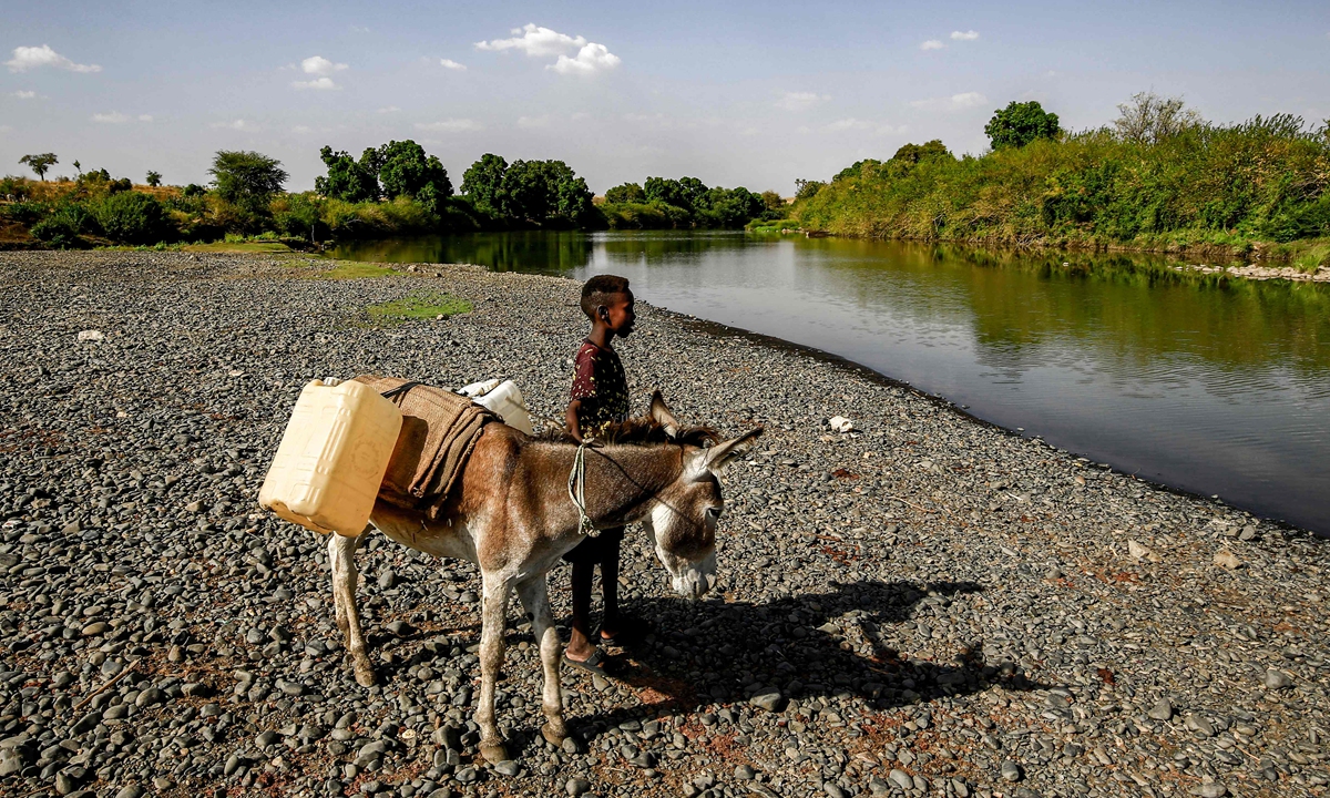A boy stands next to a donkey loaded with jerry cans by the Atbarah river near the village of Dukouli within the Quraysha locality, located in the Fashaqa al-Sughra agricultural region of Sudan's eastern Gedaref state on March 16, 2021. Photo: VCG