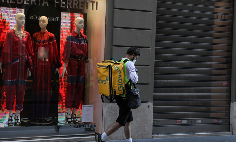 A food delivery man walks past shops closed due to the coronavirus pandemic in Rome, Italy, April 11, 2020.(Photo: Xinhua)