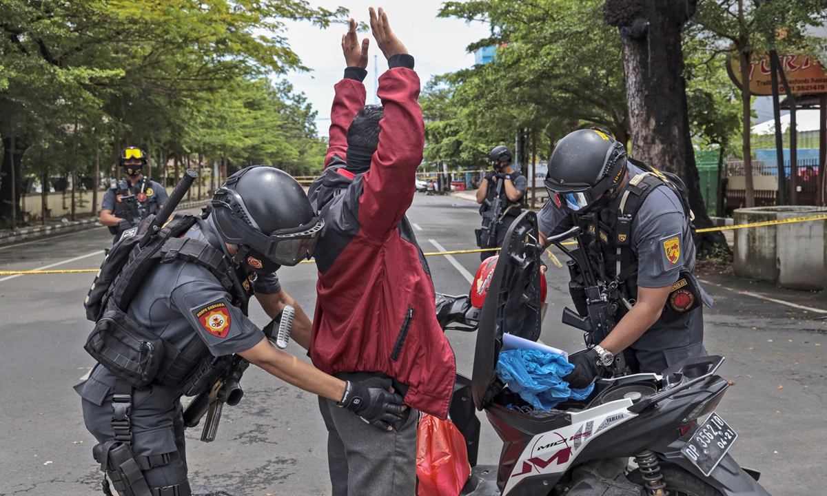 Police officers search a man at a security checkpoint near the site of Sunday's suicide bomb attack at the Sacred Heart of Jesus Cathedral in Makassar, South Sulawesi, Indonesia, Monday, March 29, 2021. Photo: VCG