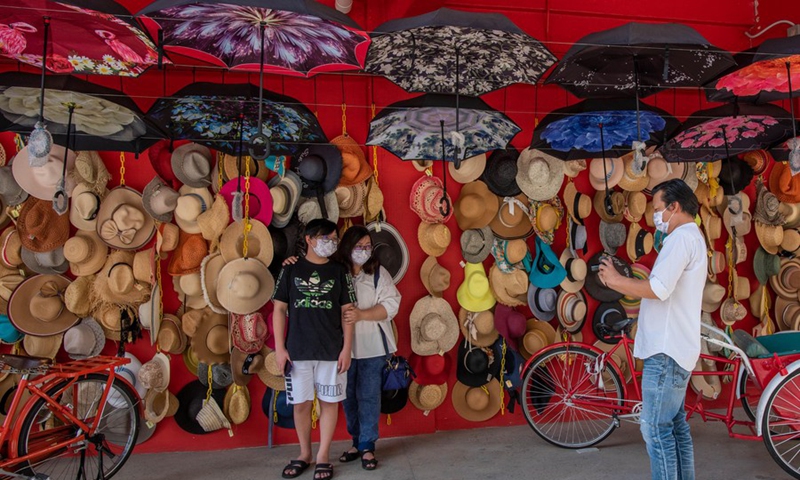 People wearing face masks pose for photos on a street in Kuala Lumpur, Malaysia, March 28, 2021.(Photo: Xinhua)