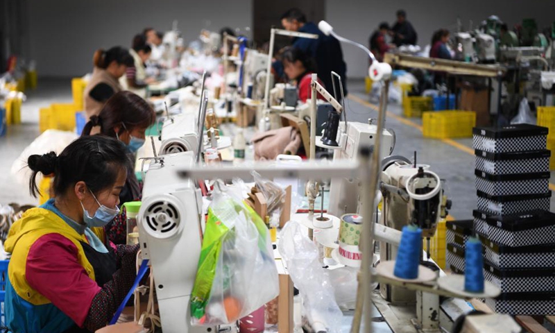 Workers are busy at a shoe factory at an industrial park in Anping Town of Fengjie County, southwest China's Chongqing, March 31, 2021. By improving infrastructure, developing electric commerce and setting up industrial park for people returning to hometown, Fengjie County has found ways to boost local development.   Photo: Xinhua