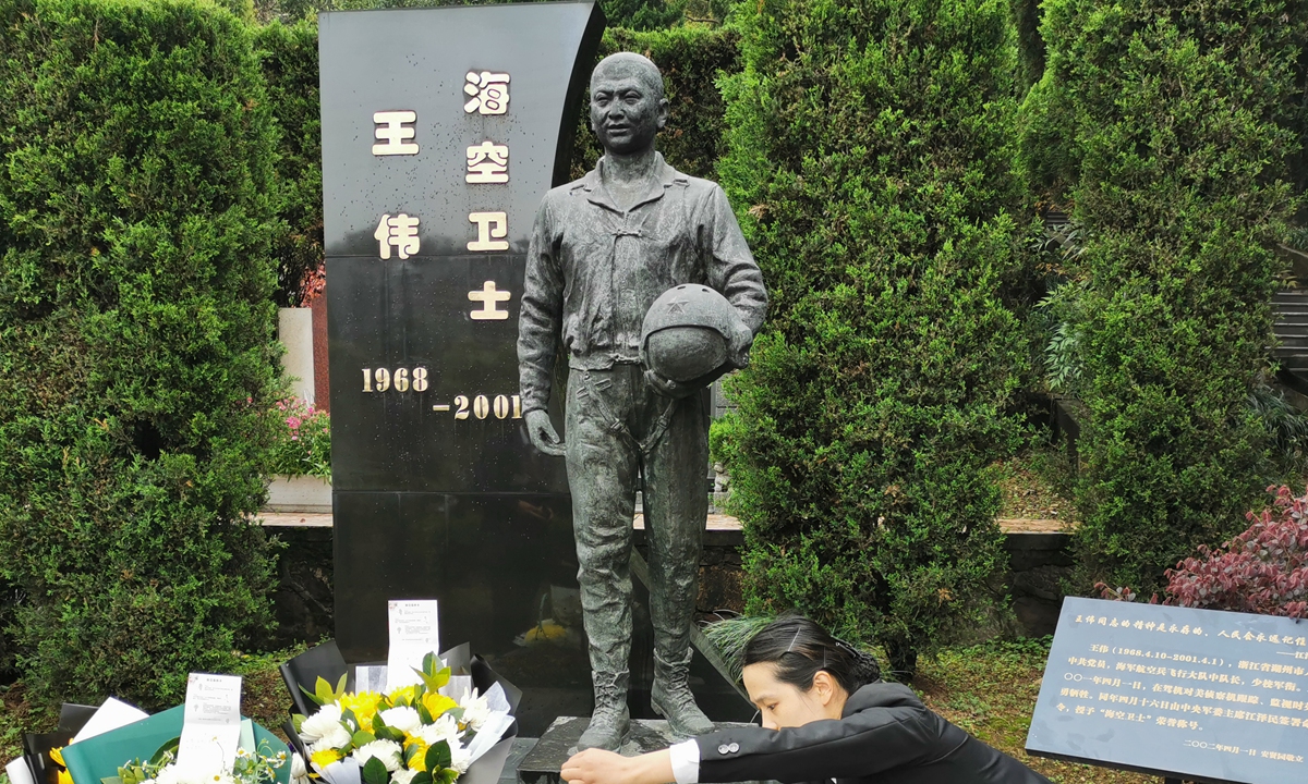 A staffer on Thursday tidies the cenotaph of Wang Wei, a heroic PLA pilot who went missing and assumed dead after his plane collided with a US spy aircraft 20 years ago. People sent flowers and notes to the hero during a commemoration in Hangzhou, East China's Zhejiang Province.  Photo: Xinhua