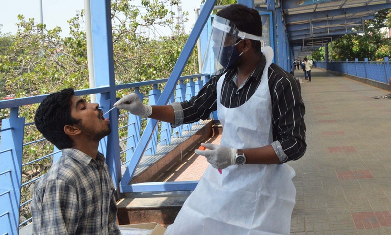 A healthcare worker collects a swab from a traveler for COVID-19 test outside a bus station in Bangalore, India, April 1, 2021. (Str/Xinhua)