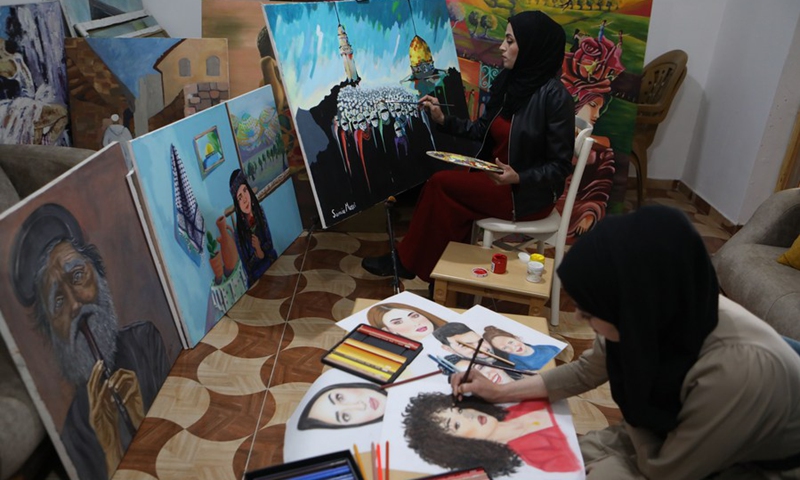Palestinian artists Doaa al-Masri (R) and her sister Samia al-Masri paint at their home in the al-Fawwar refugee camp, south of West Bank city Hebron, April 3, 2021.(Photo: Xinhua)