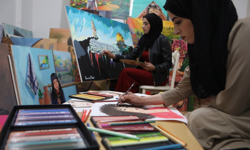 Palestinian artist Doaa al-Masri (R) and her sister Samia al-Masri paint at their home in the al-Fawwar refugee camp, south of West Bank city Hebron, April 3, 2021.(Photo: Xinhua)