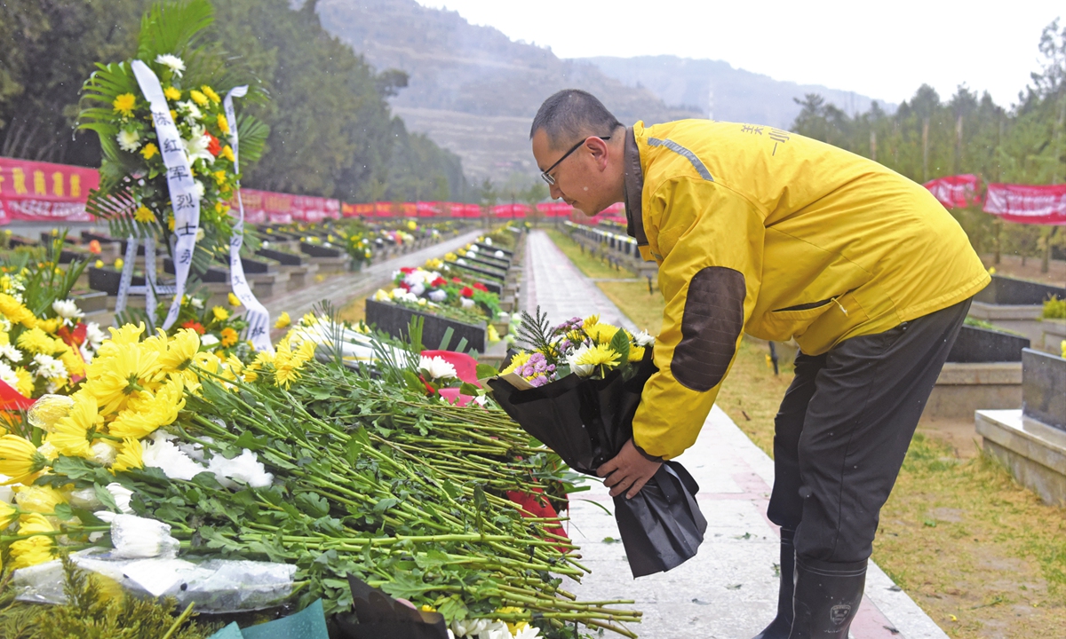 Take-away deliveryman Zhou Xiaorong presents flowers to martyr Chen Hongjun on behalf of netizens at the Martyrs' Cemetery in Lanzhou, Northwest China's Gansu Province. Photo: Xinhua