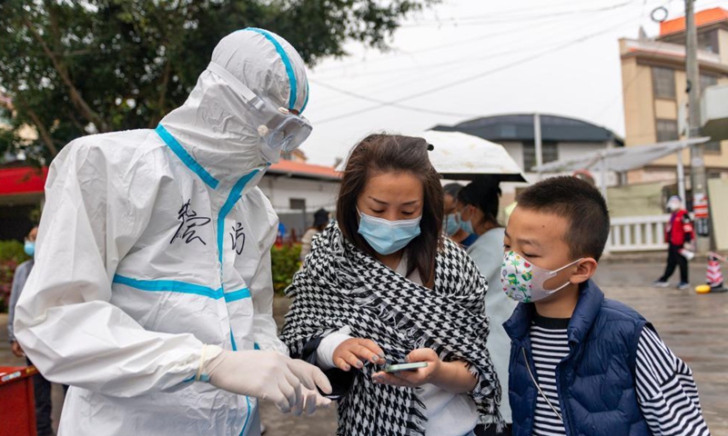 A volunteer guides residents in their registration on mobile phone before receiving nucleic acid testing for COVID-19 at Munao community, Ruili City, southwest China's Yunnan Province, April 6, 2021. Ruili City in southwest China's Yunnan Province on Tuesday launched the second round of nucleic acid testing that includes all residents of the city proper.  (Xinhua)
