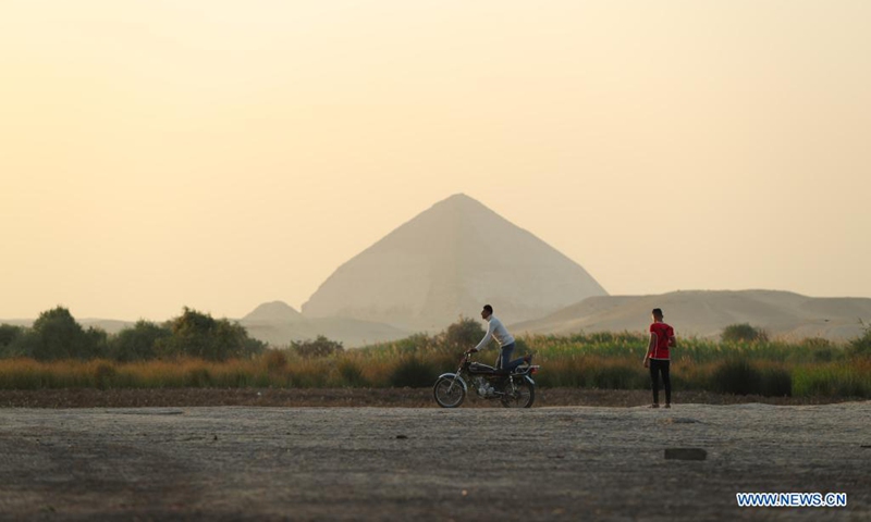 Young men ride a motorcycle near the Bent Pyramid in Giza, Egypt, April 5, 2021. The Bent Pyramid has a history of more than four thousand years, locating at Dahshur royal necropolis in Giza, south of Cairo. The pyramid was named as the Bent Pyramid or the Pyramid with Two Angles for having two different angles of inclination from base to top.(Photo: Xinhua)