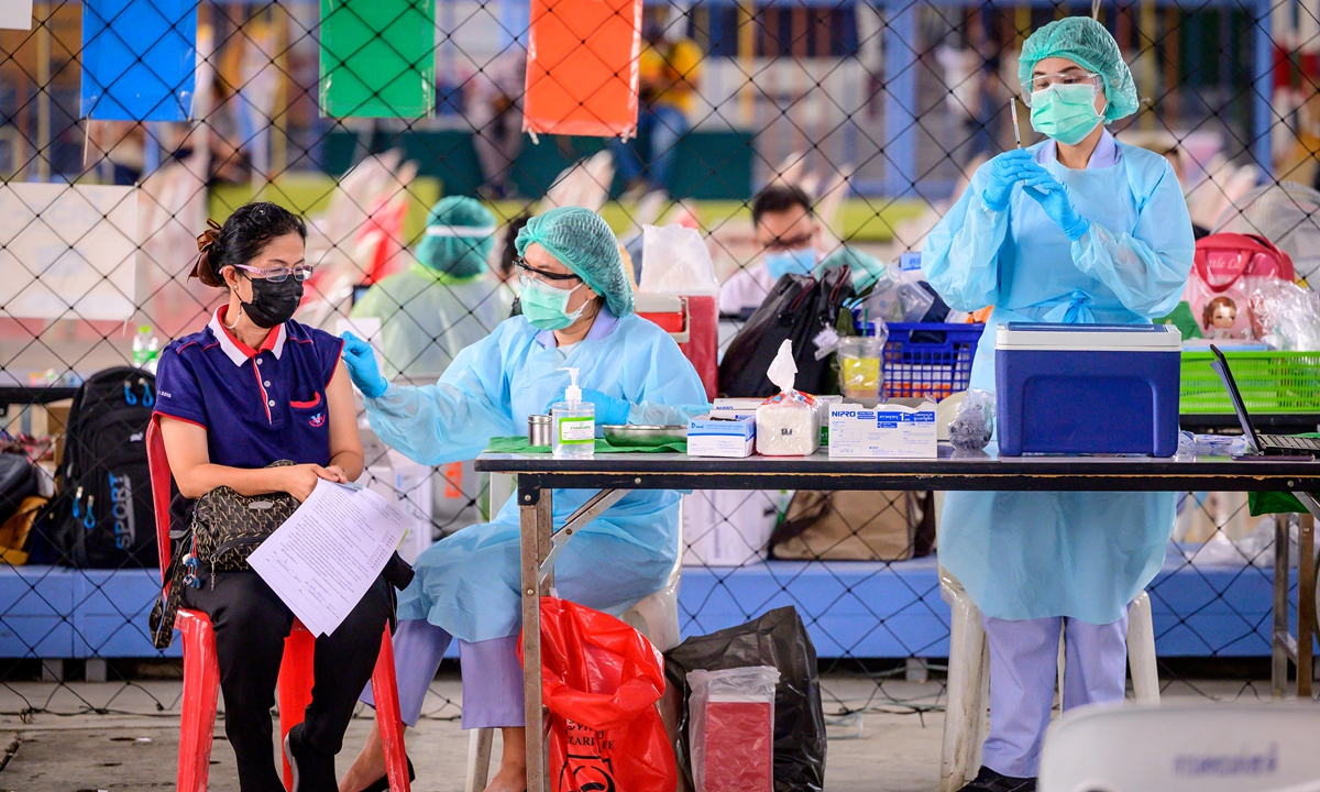 A health worker administers the CoronaVac vaccine, developed by China's Sinovac firm, to a woman from an at-risk group following a COVID-19 cluster traced to entertainment venues at a makeshift clinic, at Saeng Thip sports ground in Bangkok on Wednesday. Photo: AFP