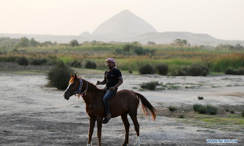 A man rides a horse near the Bent Pyramid in Giza, Egypt, April 5, 2021. The Bent Pyramid has a history of more than four thousand years, locating at Dahshur royal necropolis in Giza, south of Cairo. The pyramid was named as the Bent Pyramid or the Pyramid with Two Angles for having two different angles of inclination from base to top.(Photo: Xinhua)