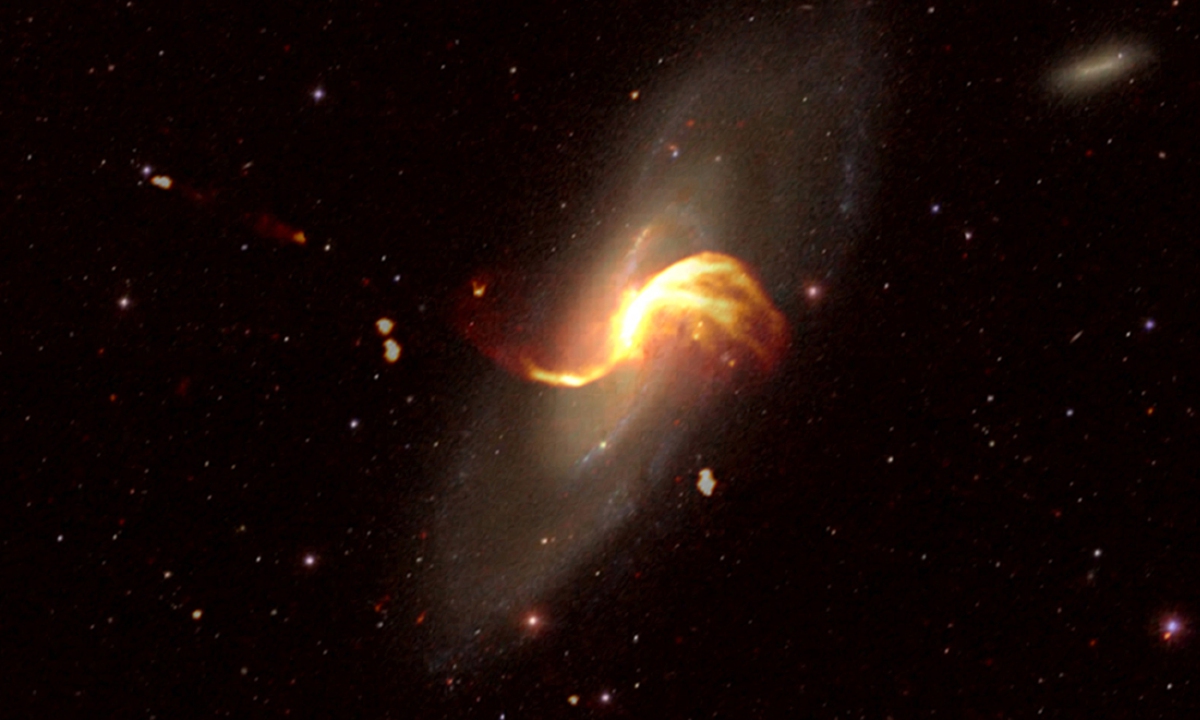 An optical image of the M106 galaxy stacked on an image of the galaxy's emissions of material (in orange) taken with the Low-Frequency Array (LOFAR) radio telescope, on February 19, 2019. Photo: AFP