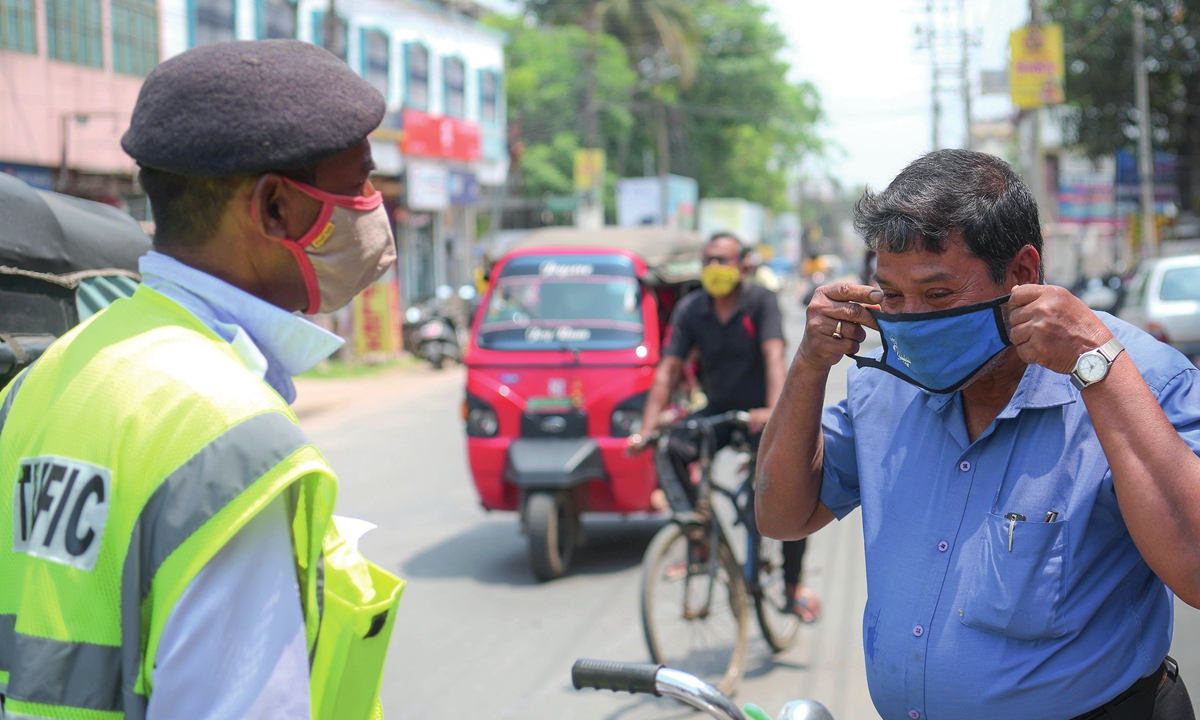 A policeman in Agartala, the capital city of the Indian state of Tripura, fines a local resident who had not worn a mask on Friday. The number of COVID-19 cases in India surpassed 13 million on that day. Photo: Xinhua