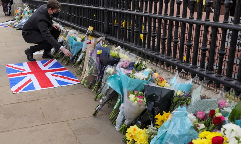 A man leaves a flower tribute at the gates of Buckingham Palace in London, Britain, on April 9, 2021.(Photo: Xinhua)