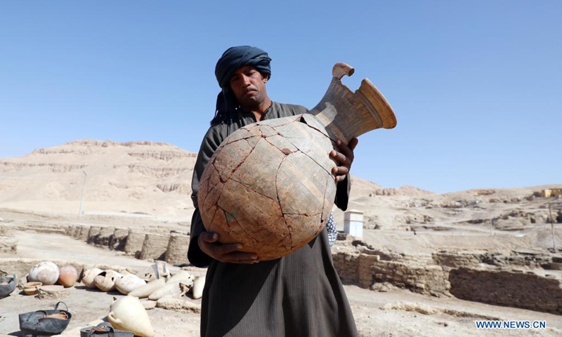 An excavation worker carries a pottery vessel unearthed from the archeological site of the Lost Gold City in Luxor, Egypt, April 10, 2021. An Egyptian archeological mission announced on Thursday the discovery of a 3,000-year-old Lost Gold City (LGC) in Egypt's monument-rich city of Luxor.(Photo: Xinhua)