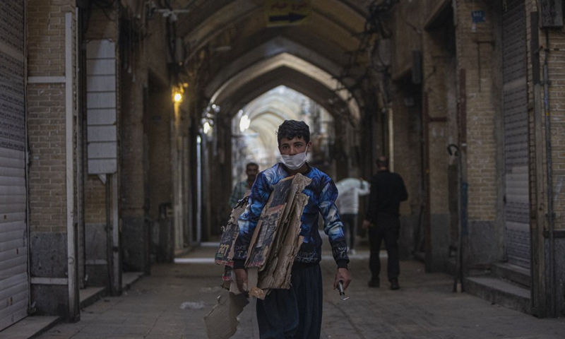 A boy with a face mask walks past closed shops at the Grand Bazaar in Tehran, Iran, April 10, 2021.(Photo: Xinhua)