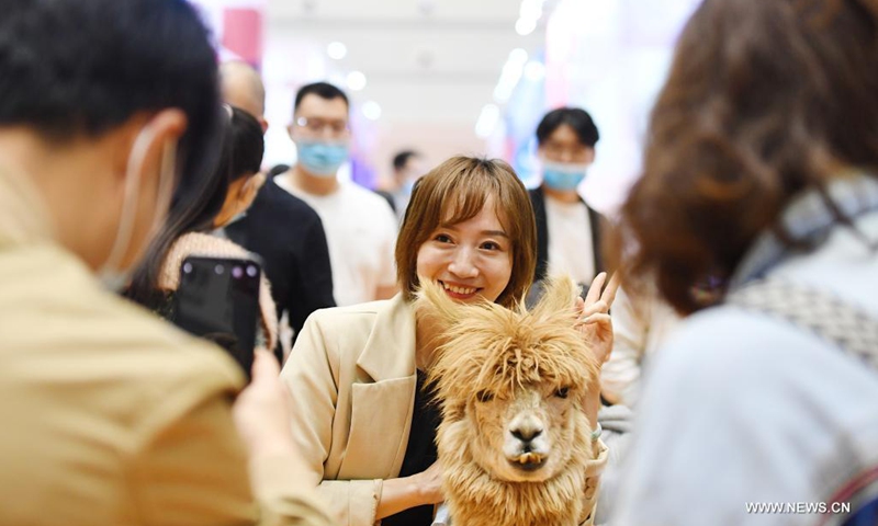A woman poses with an alpaca during a pet expo held from April 9 to April 11 in Zhengzhou, central China's Henan Province, April 10, 2021.(Photo: Xinhua)