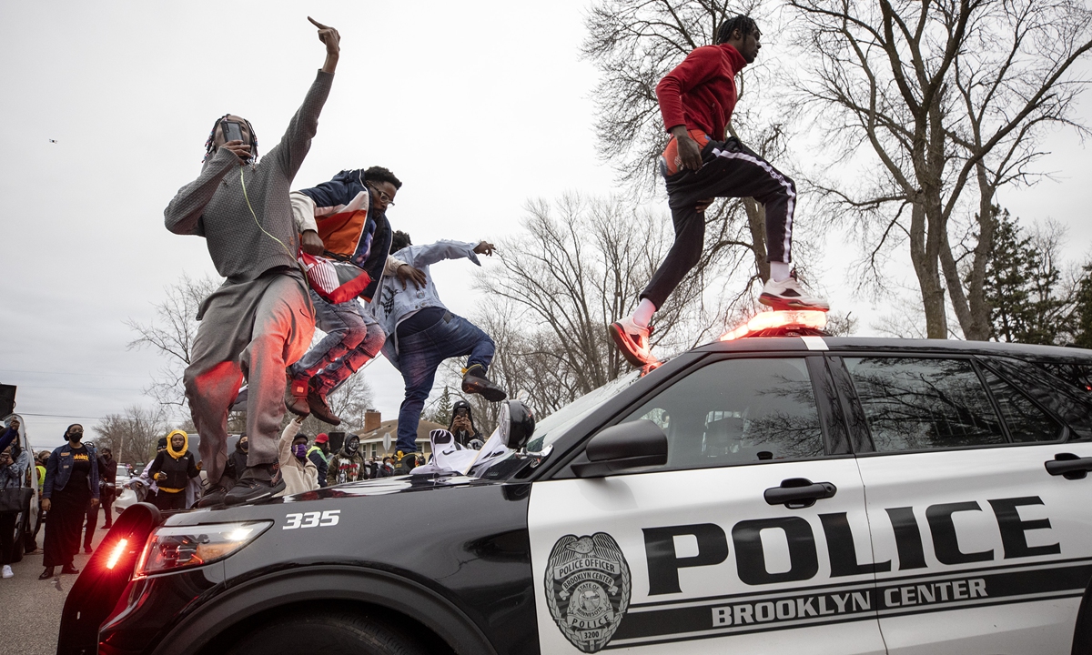 Men jumped on police vehicles near the site of an officer involved shooting and killing of Daunte Wright during a traffic stop on April 11. Photo: VCG