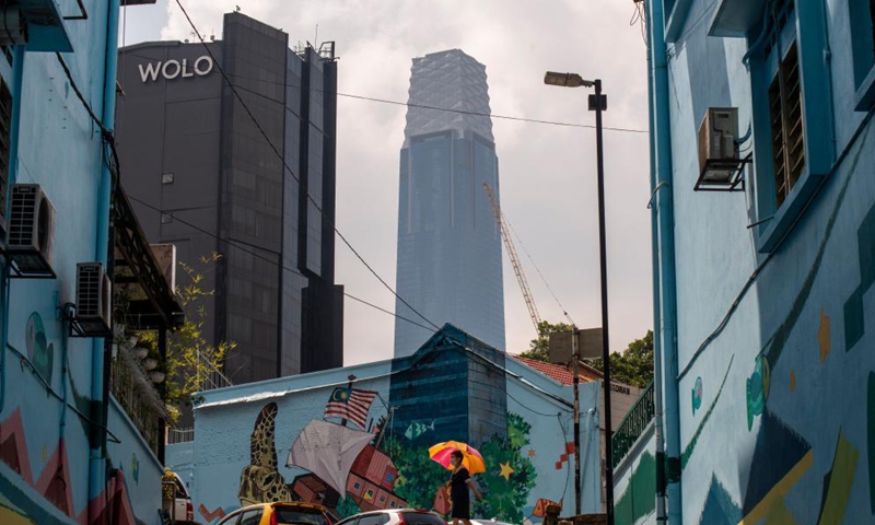 A pedestrian walks near a mural seamlessly melted with the Exchange 106 tower in the background in Kuala Lumpur, Malaysia, April 15, 2021. Photo: Xinhua