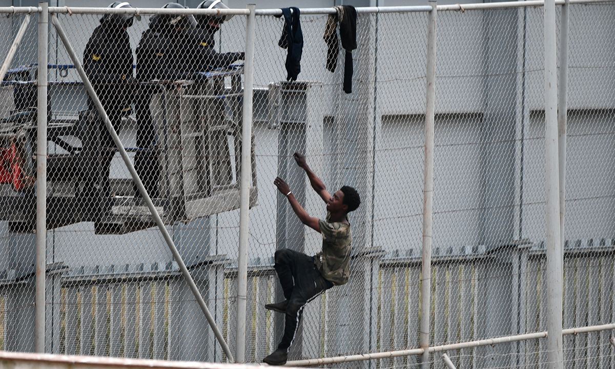 A youth tries to climb over the border fence in the Spanish exclave of Ceuta bordering Morocco on Tuesday. Melilla and Ceuta, another Spanish territory in North Africa, have the European Union's only land borders with Africa, making them popular entry points for migrants seeking a better life in Europe. Photo: AFP