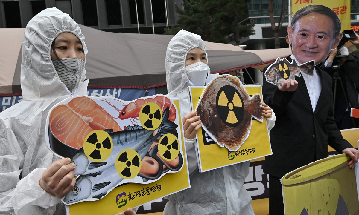 South Korean environmental activists wearing protective clothing and a mask (right) of Japan's Prime Minister Yoshihide Suga hold pictures of fish with radioactivity warning signs during a protest against Japan's decision on releasing Fukushima wastewater, near the Japanese embassy in Seoul on Tuesday. Photo: VCG