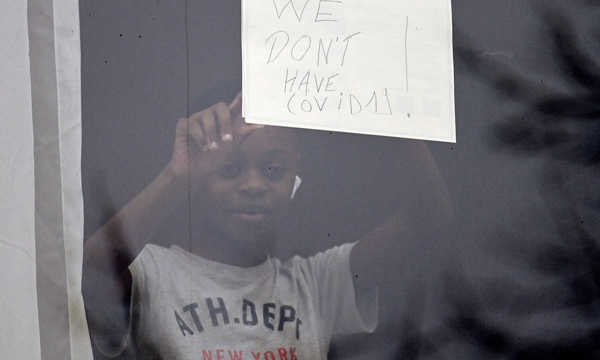 A quarantining passenger holds up a sign reading  We don't have COVID-19! after having to isolate for 10 days at the Radisson Blu hotel on February 16, 2021 in London, the UK. Photo: VCG

