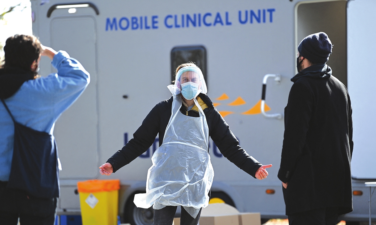 A worker dressed in personal protective gear talks with members of the public arriving to take COVID-19 tests at a mobile novel coronavirus surge testing center in Brockwell Park, London on Tuesday. The UK has eased its lockdown further with the reopening of non-essential shops and pub beer gardens on Monday while COVID-19 cases in the country approached 44 million with about 127,100 deaths as of Tuesday. Photo: AFP