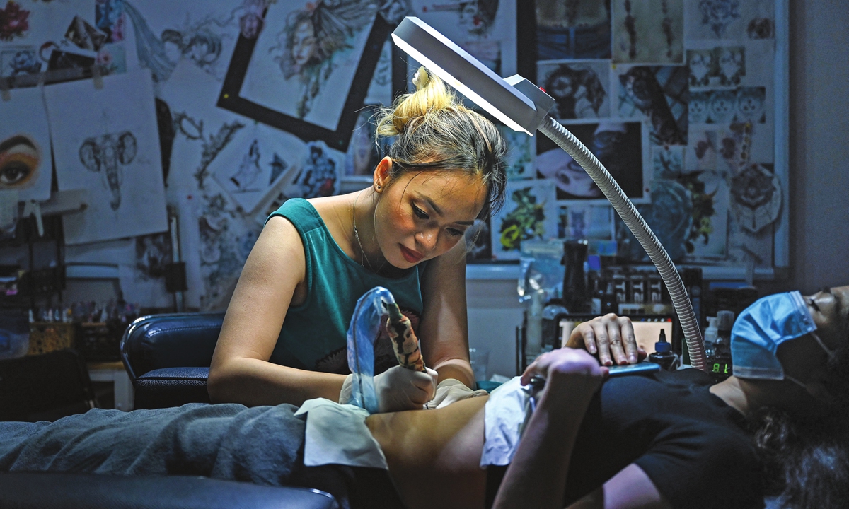Tattoo artist Ngoc Like designs a tattoo over a female customer's scar at her studio in Hanoi, Vietnam, on March 20. Photo: AFP