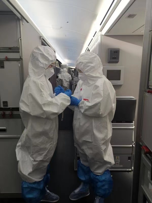 Cabin crew members help each other put on protective suits. Photo: Courtesy of Air China  