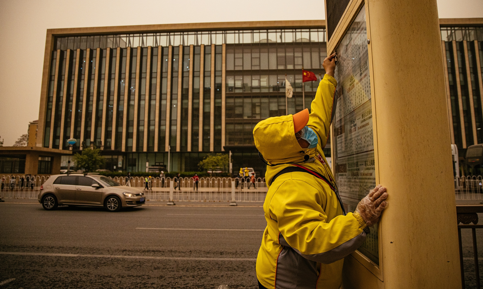 A traffic staff member wipes a bus stop billboard in the wind, accompanied by rain and mud in Shijingshan district, Beijing on Thursday. Beijing experienced a new wave of sandstorms with muddy rainfall on Thursday afternoon, triggering a blue alert for sandstorms. Photo: Li Hao/GT