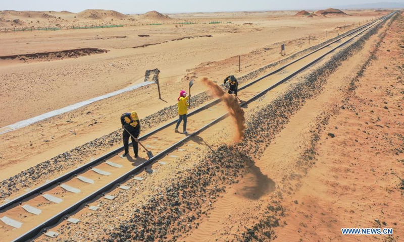 Aerial photo shows workers removing sand along Linhe-Ceke railway in north China's Inner Mongolia Autonomous Region, April 14, 2021. With a total length of 768 kilometers, the Linhe-Ceke railway is one of the important junctions connecting Mongolia and China. 