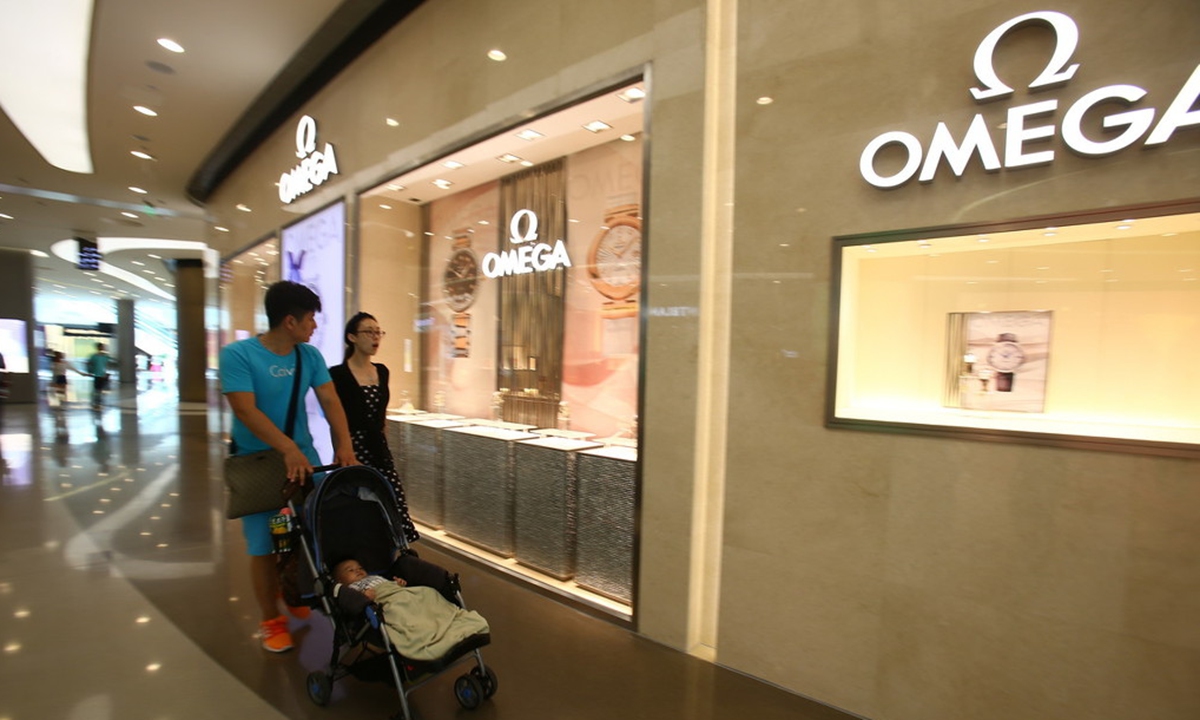 Pedestrians walk past an advertisement for Omega watches in Guangzhou, China, on September 27, 2014. Photo: IC