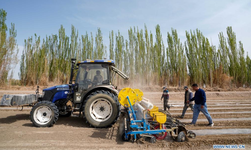 Cotton farmer Dilshat Memet (1st R) and employees have a discussion on film mulching sower efficiency in a cotton field in Tungqeka Village of Xingping Township, Yuli County, Bayingolin Mongolian Autonomous Prefecture, northwest China's Xinjiang Uygur Autonomous Region, April 13, 2021. Photo:Xinhua