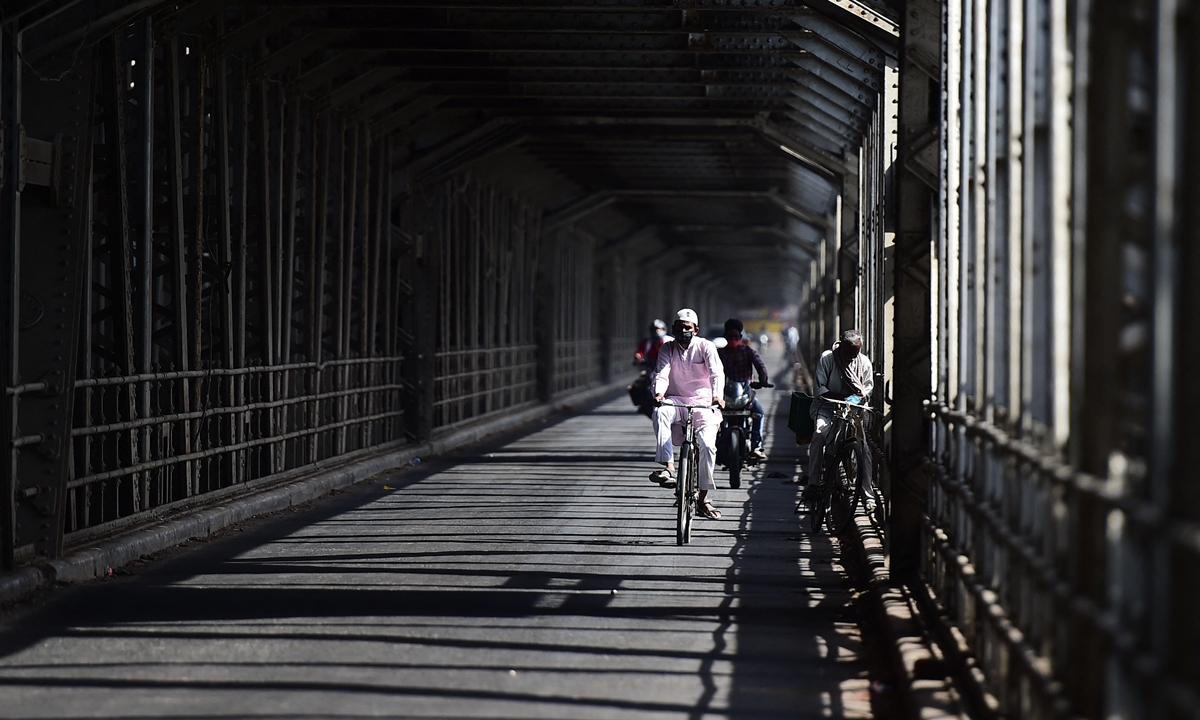 A man rides a bicycle on an empty bridge during a weekend lockdown imposed by the government as a preventive measure against the COVID-19 epidemic in Allahabad, India, on Sunday. India recorded a new high of more than 261,000 daily coronavirus cases in the past 24 hours, the country's health ministry said Sunday. Photo: AFP