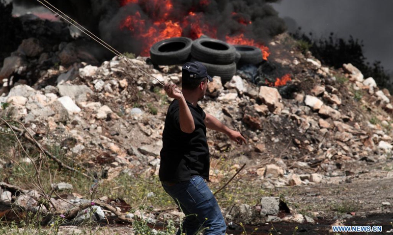 A Palestinian protester uses a slingshot to throw stones at Israeli soldiers during clashes after a protest against the expansion of Jewish settlements in Kufr Qadoom village near the West Bank city of Nablus, on April 16, 2021.(Photo: Xinhua)