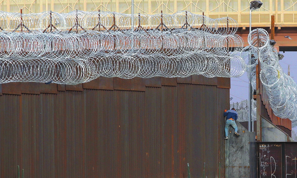 A Haitian migrant climbs the Mexico-US border fence near the El Paso border crossing, in Ciudad Juarez, Chihuahua state, Mexico on Thursday. Photo: AFP