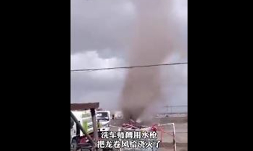 An old man washing his car quells the rampaging wind of tornado in Central China's Hubei Province. Photo: Screenshot of a video posted by Kan Kan news


