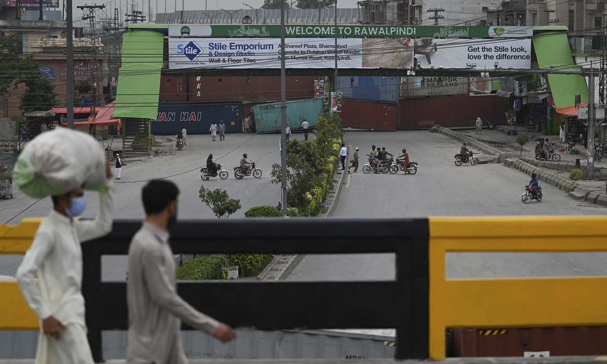 People return on the main entry point between Rawalpindi and Islamabad, Pakistan which was blocked with shipping containers as authorities secured the area and beefed up security following violent anti-France protests called by radical Tehreek-i-Labbaik Pakistan in Rawalpindi on Tuesday. Photo: AFP