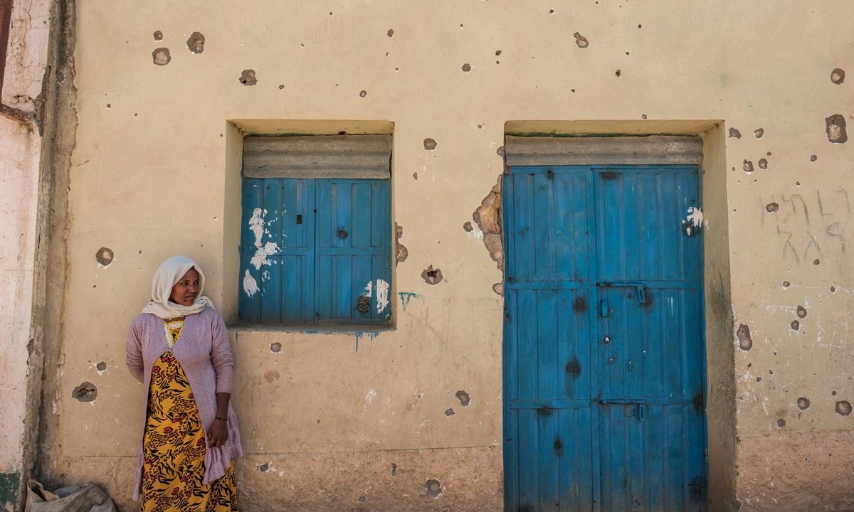 A woman leans on the wall of a damaged house which was shelled as federal-aligned forces entered the city, in Wukro, north of Mekele, on March 1, 2021.Photo: VCG