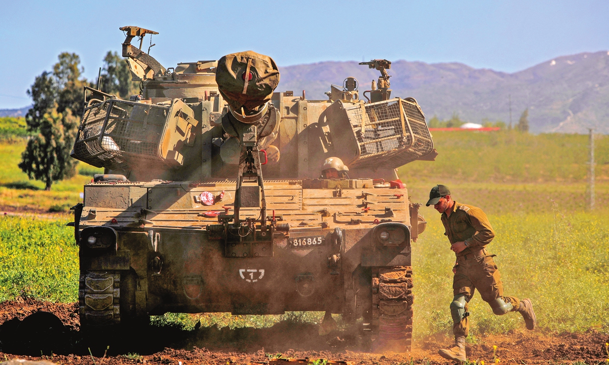An Israeli soldier runs past an M109 howitzer mobile artillery cannon at a position near Moshav Sha'al in the Israeli-occupied Golan Heights, on Thursday. The Israeli military struck multiple Syrian targets after a missile targeted southern Israel near a secretive nuclear site, the army said early Thursday. Photo: AFP