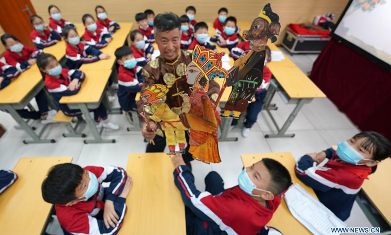 An artist shows shadow puppets to students at the No. 6 Middle School in Shahe City, north China's Hebei Province, April 21, 2021. The middle school has invited local artists to introduce the traditional shadow play to students as a part of effort to have its students better know intangible culture heritage.(Photo: Xinhua)
