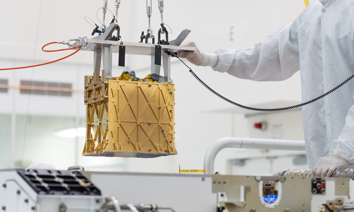 Technicians in the clean room carefully lowering the Mars Oxygen In-Situ Resource Utilization Experiment (MOXIE) instrument into the belly of the Perseverance rover in the cleanroom at NASA's Jet Propulsion Laboratory, in Pasadena, California in March 2019. Photo: VCG