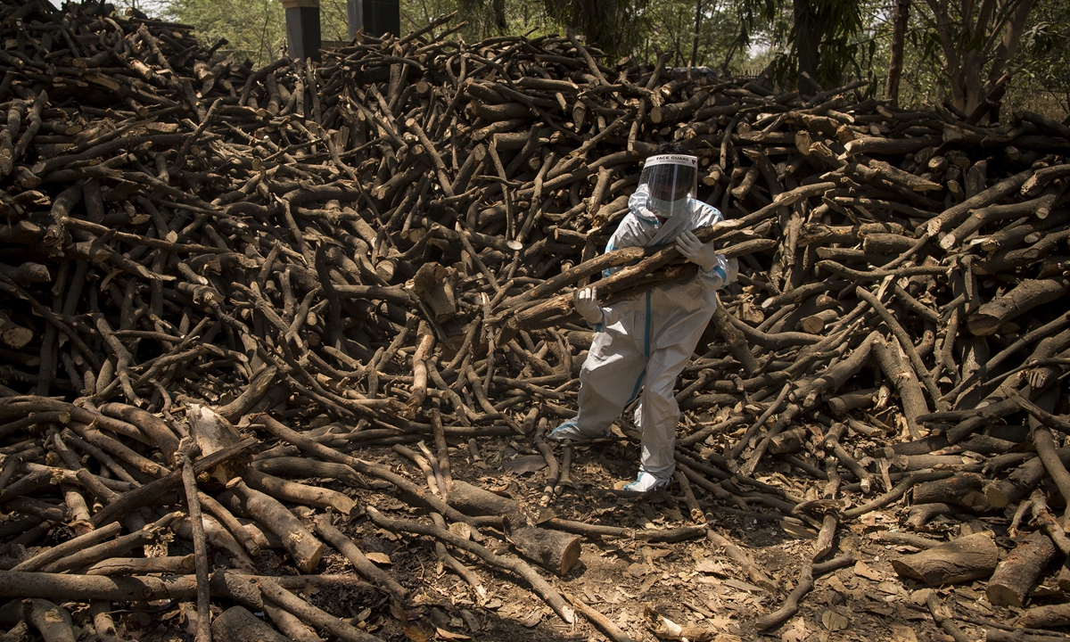 Cemetery workers wearing PPE kits (personal Protection Equipment) sort logs of wood for the funeral pyres to perform the last rites of the patients who died of the Covid-19 coronavirus disease on April 22, 2021 at a crematorium in the outskirts of New Delhi, India. Photo: VCG