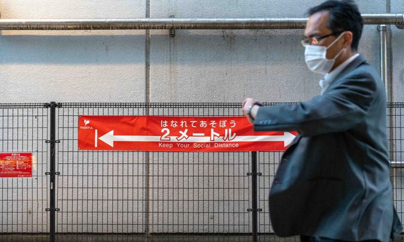 A man walks past a social distancing banner in Tokyo, Japan on April 23, 2021. Japan's Prime Minister Yoshihide Suga on Friday declared a third state of emergency over COVID-19 in Tokyo, Osaka, Kyoto and Hyogo. The state of emergency will come into effect from Sunday to May 11.Photo:Xinhua