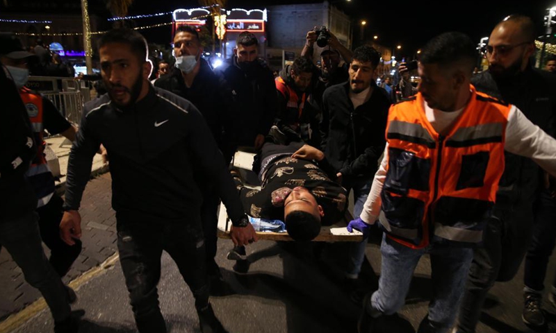 People carry an injured man during clashes between Palestinians and Israelis in east Jerusalem, on April 22, 2021. Dozens of people were injured and dozens more arrested as clashes erupted between Palestinians and Israelis in east Jerusalem on Thursday night.Photo:Xinhua