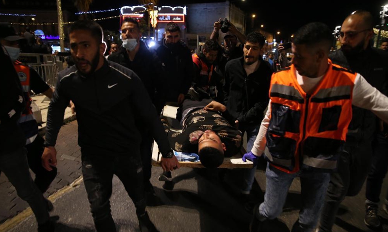 People carry an injured man during clashes between Palestinians and Israelis in east Jerusalem, on April 22, 2021. Dozens of people were injured and dozens more arrested as clashes erupted between Palestinians and Israelis in east Jerusalem on Thursday night.Photo:Xinhua