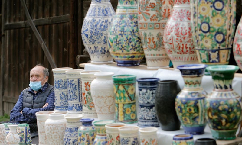 An artisan waits for customers during a traditional spring handmade craft fair organised at Romania's Village Museum in Bucharest, Romania, April 24, 2021. Artisans from all around the country arrived at the Village Museum to prove their crafting talents and to sell their goods.(Photo: Xinhua)