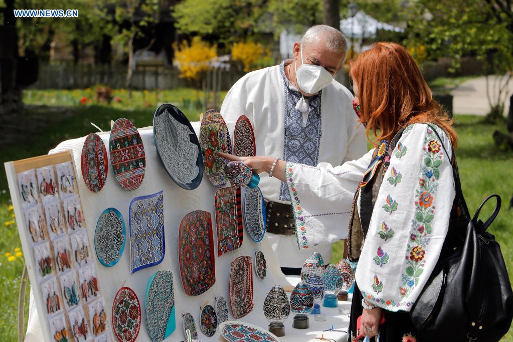 An artisan presents his goods to a customer during a traditional spring handmade craft fair organised at Romania's Village Museum in Bucharest, Romania, April 24, 2021. Artisans from all around the country arrived at the Village Museum to prove their crafting talents and to sell their goods. (Photo: Xinhua)
