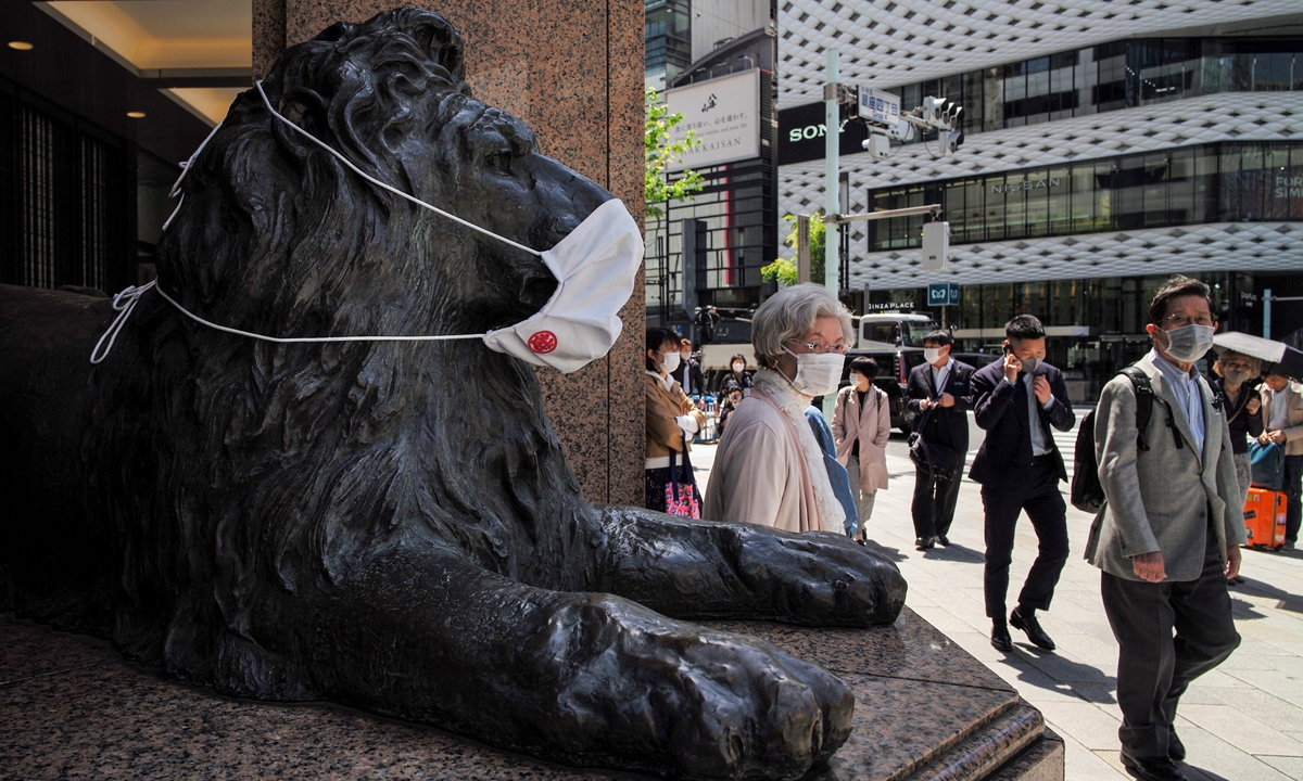 Pedestrians walk in front of a lion statue, the mascot of a department store, wearing a mask in Tokyo on Monday, during a new coronavirus state of emergency covering Tokyo, Osaka, Kyoto and Hyogo regions. The country struggles to contain a resurgent coronavirus pandemic three months before the Olympics. Photo: AFP