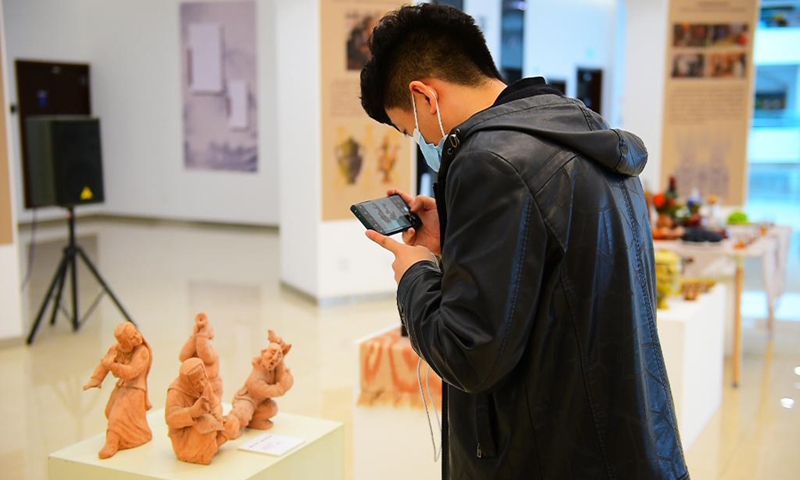 A visitor takes photos of exhibits at an exhibition of traditional crafts with Xinjiang characteristics in Urumqi, northwest China's Xinjiang Uygur Autonomous Region, April 26, 2021. (Xinhua/Hou Zhaokang) 